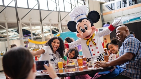 Una familia de 4 personas posa para una foto con Mickey Mouse en el restaurante Chef Mickey's