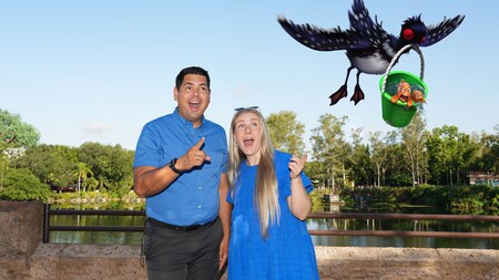 A couple posing with an augmented reality overlay of Becky the bird carrying Marlin and Nemo in a bucket