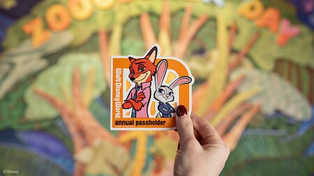 A hand holding a Walt Disney World Annual Passholder magnet featuring Nick Wilde, Judy Hopps and text that reads ‘Walt Disney World Annual Passholder’