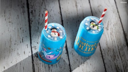 Two Epcot International Festival of the Holidays glasses featuring Figment, both filled with a slushie beverage and decorated with edible snowman and snowflake toppings