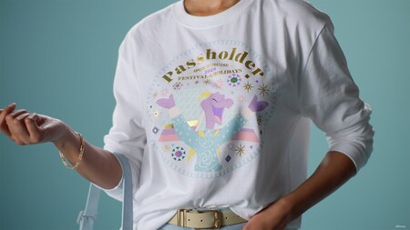 A person wearing a white long sleeve T shirt featuring Figment and the word ‘Passholder’ above Epcot International Festival of the Holidays 2025