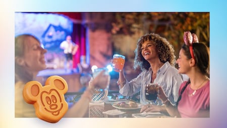 Three friends hold up their glasses during a meal and an illustration of a Mickey waffle