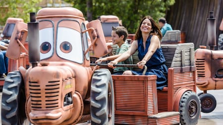 A mother and son smiling as they ride Mater’s Junkyard Jamboree