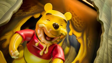 Una estatua de Winnie the Pooh sonriente emergiendo de un panal en un árbol con la boca y una mano cubiertas de miel