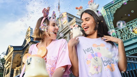 Two women smiling together while wearing Halloween merchandise including Minnie Mouse ear headbands and T shirts