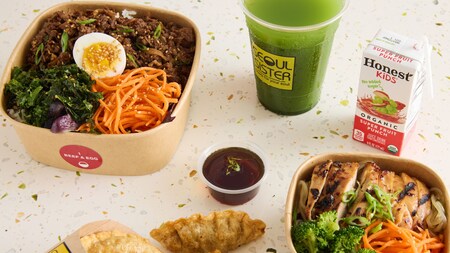 A beef and egg bowl, a chicken bowl, a side of dumplings, a cup of matcha iced tea and a fruit punch juice box