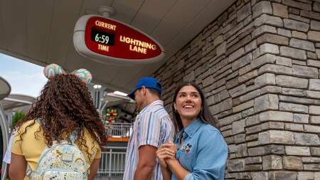 Several Guests waiting beneath a Lightning Lane sign displaying the current time