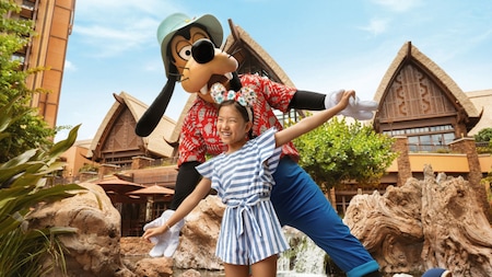 A young girl posing with Goofy at Aulani, A Disney Resort & Spa