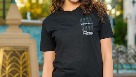 A woman wearing a short sleeve T shirt featuring the logo for the 25th anniversary of Magic Key at Disney California Adventure Park