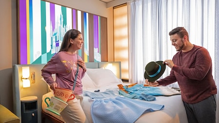 A couple looking at their Disney themed accessories while inside of their hotel room