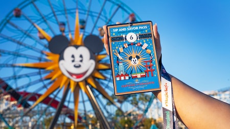A Guest holds a Sip and Savor Pass on a lanyard for the Disney Festival of Holidays