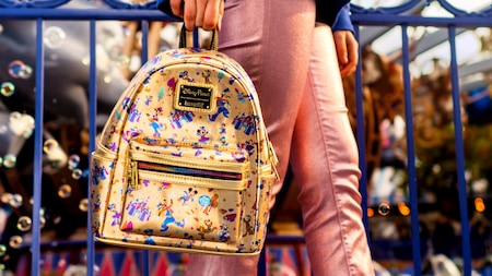 A Guest carrying a Mickey Mouse and Friends Disneyland 70th Anniversary Lounge fly Mini Backpack