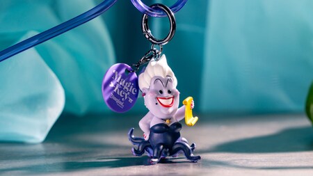 A Magic Key straw clip with an Ursula figure holding a scroll