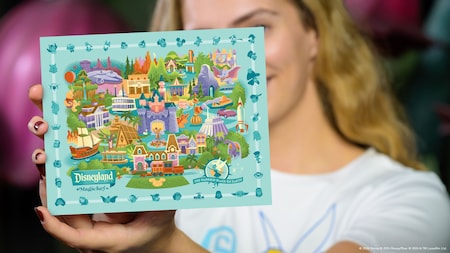 Visitante con una pequeña postal de Magic Key de Disneyland Resort en la que aparece un mapa del Parque