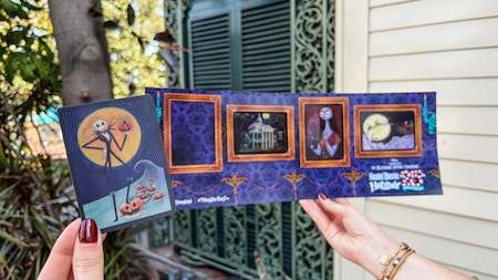 Two hands holding a Magic Key card and pamphlet featuring Jack the Skeleton and The Haunted Mansion Holiday logo