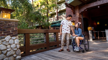 A man stands next to a woman in a wheelchair near the entrance to Disney’s Grand Californian Hotel & Spa