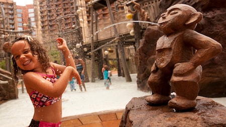 A little girl in the splash zone within the Aulani Resort pool area