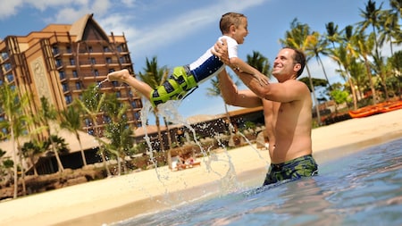 A father and son playing in the beach lagoon at Aulani Resort