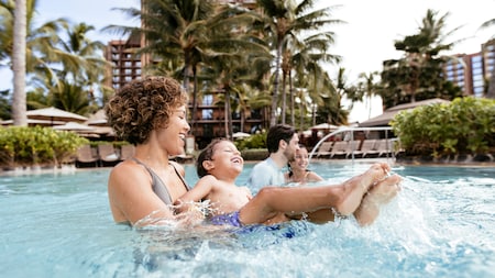 A family of 4 playing in a pool at Aulani Resort