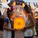 Two smiling young girls wearing Minnie ear headbands face one another while holding on to an illuminated lantern