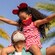 A little girl sits on her father's shoulders in an outdoor setting with palm trees