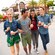 Four smiling young adults walk arm in arm through Downtown Disney District while holding cups of ice cream