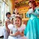 A little girl beams as her brother and sister share a laugh with Princess Ariel in the background