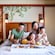 A family sits together on a hotel room bed while enjoying Mickey waffles and fruit