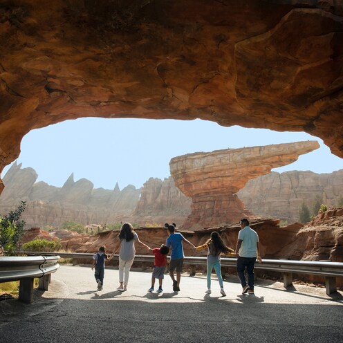 A family of six walks hand in hand through the rocky landscape of Radiator Springs