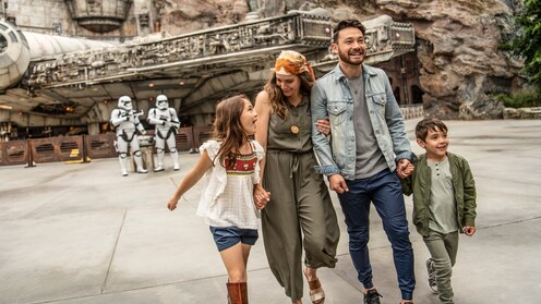 Una familia en Star Wars: Galaxy's Edge, con Stormtroopers de la Primera Orden y el Millennium Falcon de fondo