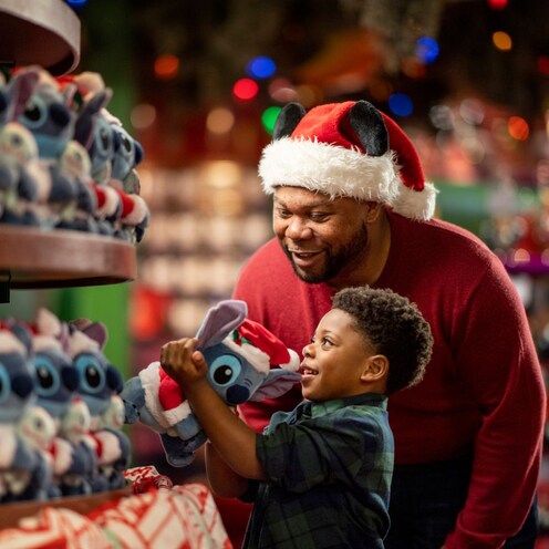 Un padre y su hijo pequeño compran juguetes de peluche de Disney en una tienda