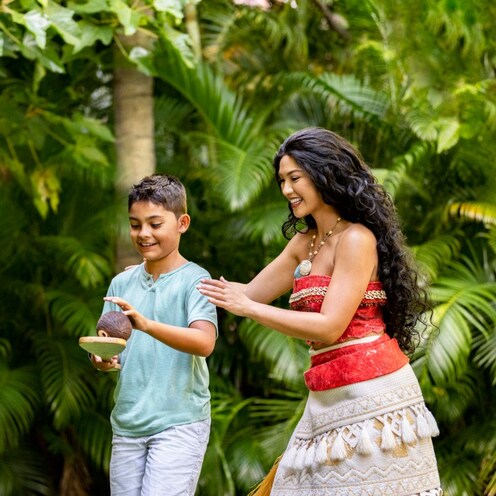 Moana greets a boy, who is holding a small oar and a coconut