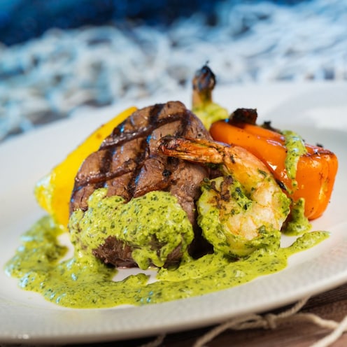 The Coral Reef Restaurant Surf and Turf entrée with a filet, shrimp and sauce on a plate 