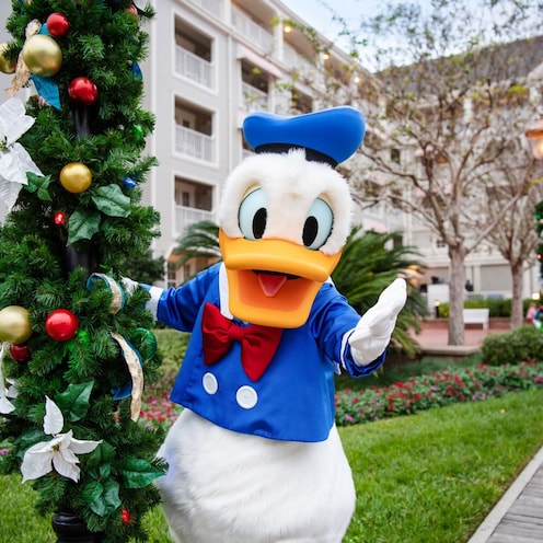 Donald Duck posando junto a un poste de luz con guirnalda festiva en Disney’s Yacht Club Resort