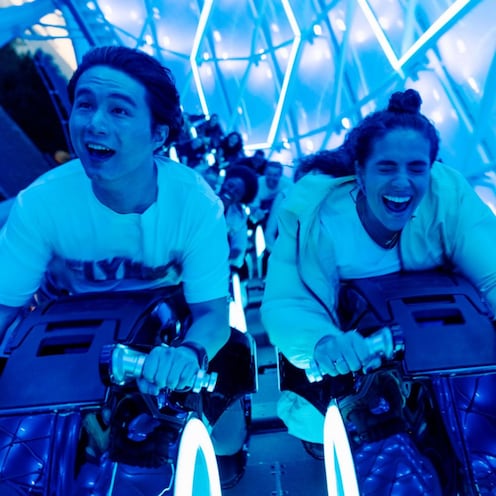 Two people smile while riding the Tron Lightcycle Run attraction at Walt Disney World Resort