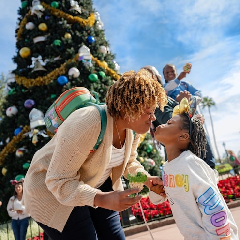 Two parents and their son eating Christmas cookies in front of a Christmas tree at The American Adventure at Epcot