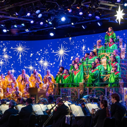 Singers in holiday themed attire and an orchestra performing in the Candlelight Processional at Epcot