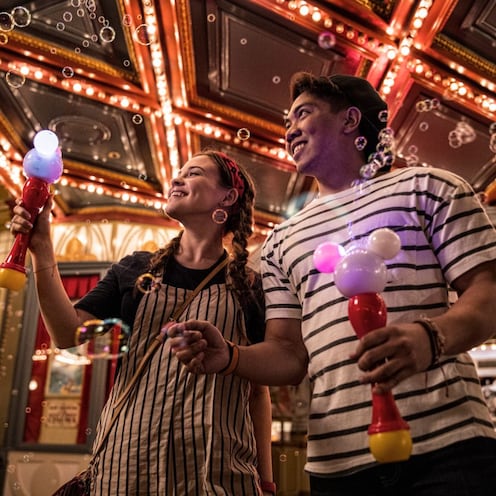 A couple holding up Mickey Mouse Light Up Bubble Wands at Main Street USA in Magic Kingdom park