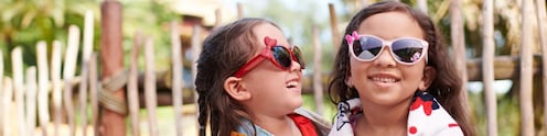 Dos chicas envueltas en toallas de playa, con lentes de sol, abrazadas