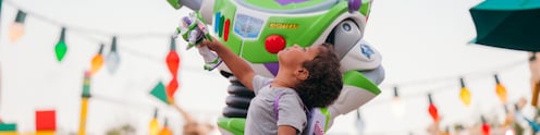 A boy standing next to Buzz Lightyear in Toy Story Land