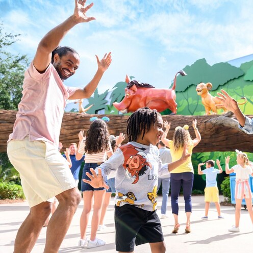 Family dancing outdoors in the Pride Lands courtyard area at Disney’s Art of Animation Resort