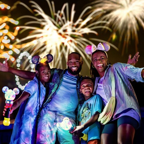 A family posing near aerial fireworks at Walt Disney World Resort