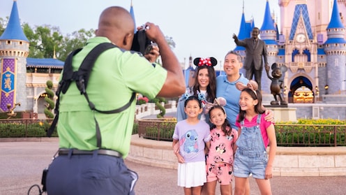 A family of 5 posing for a Disney PhotoPass photographer in front of Cinderella Castle at Magic Kingdom park