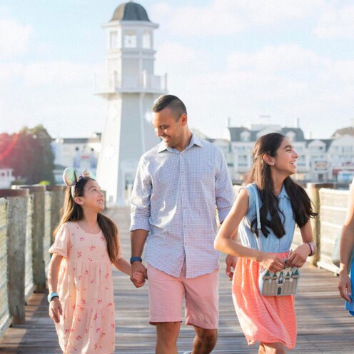 Um casal com duas filhas em um deque perto do Disney’s Yacht Club Resort e do Disney’s Beach Club Resort