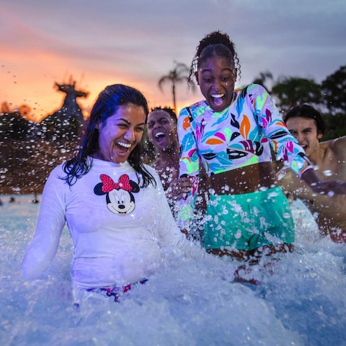 Four Guests joyfully splashing through the foamy waters of Typhoon Lagoon Surf Pool during Disney H2O Glow After Hours