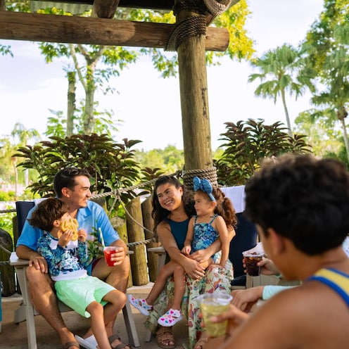 A family of 6 engaged in conversation at a Beachcomber Shack in Disney’s Typhoon Lagoon water park