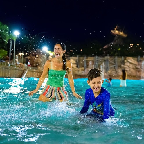 Two young Guests with their mother playing in the waters of Typhoon Lagoon Surf Pool during Disney H2O Glow After Hours