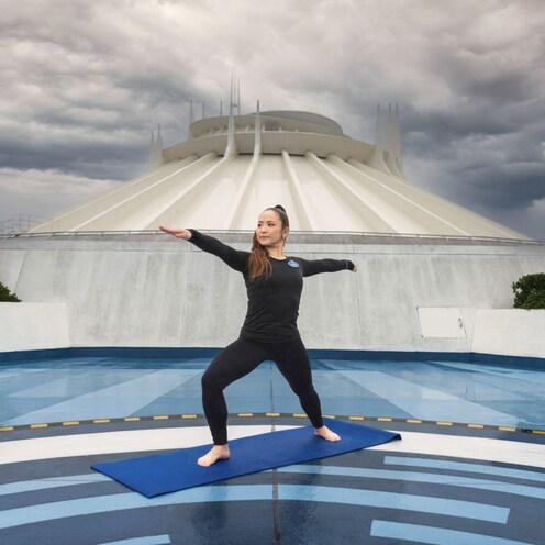 Un Miembro del Elenco de Disney haciendo una pose de yoga en una azotea.