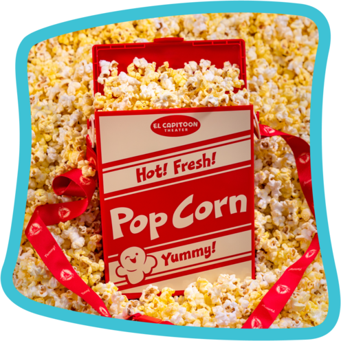 A red popcorn bucket in a pile of popcorn