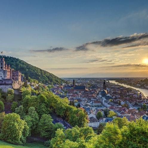 A castle looms over a charming town on a river A castle looms over a charming town on a river